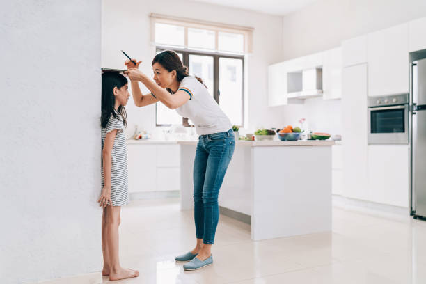 Let's see how much you have grown! Mother measuring the height of her daughter on the kitchen wall measuring a room stock pictures, royalty-free photos & images
