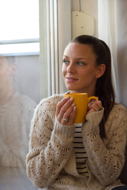 istock Woman drinking coffee beside window 1018375042