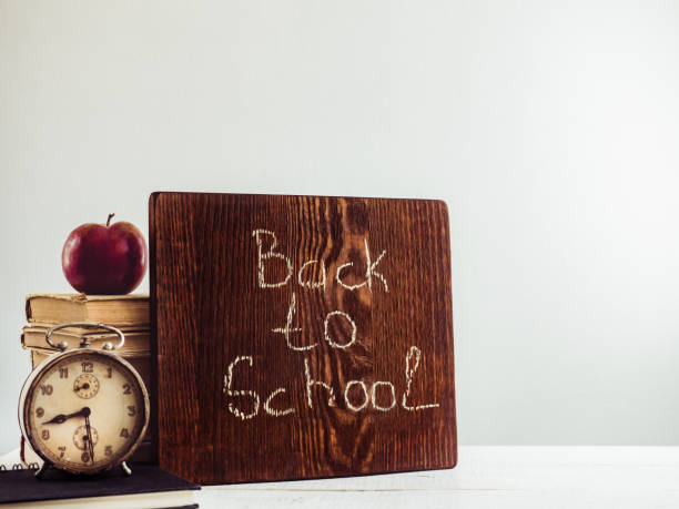 винтажные книги, старые часы, карандаши, красное яблоко и доска - book brown apple education стоковые фото и изображения