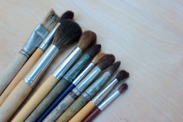 istock Watercolor paint brushes against wooden background 1018387396