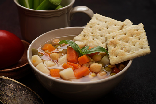 Homemade green peas with carrot and chicken meat in a pan, close up on a blue wooden table top