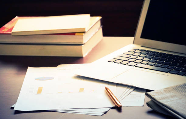 istock Working table which have chart paper and pen and newspaper and notebook and stack of books. 1018389950