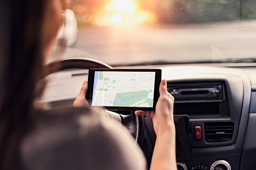 Close-up Of A Person Sitting In A Car Using GPS Service On Digital Tablet