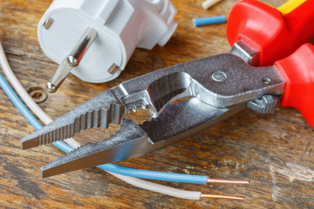istock Combination pliers for wiring with electrical plug and copper wires on wooden table in workshop 1018404204