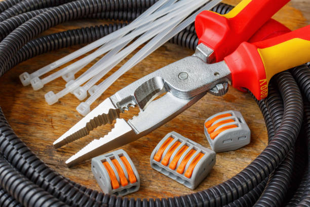 istock Plastic corrugated pipe for wiring with combination pliers and quick-release wire terminal on wooden table in workshop 1018404210