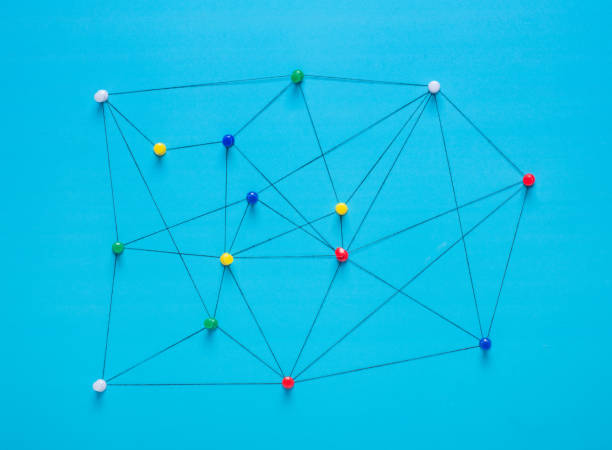 istock Small network of pins (Thumbtack)and string, An arrangement of colourful pins linked together with string on a pale background suggesting a network of connections. 1018411212