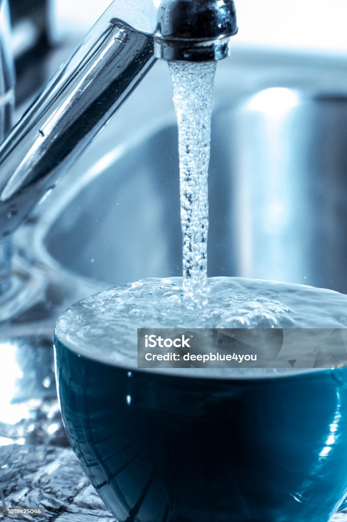 Fill in drinking water in a cup . Blue Stock Photo