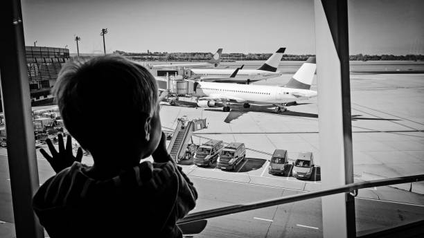 2 歳の少年の時計憧れターミナル パイロットになるの夢から飛行機 - longingly ストックフォトと画像