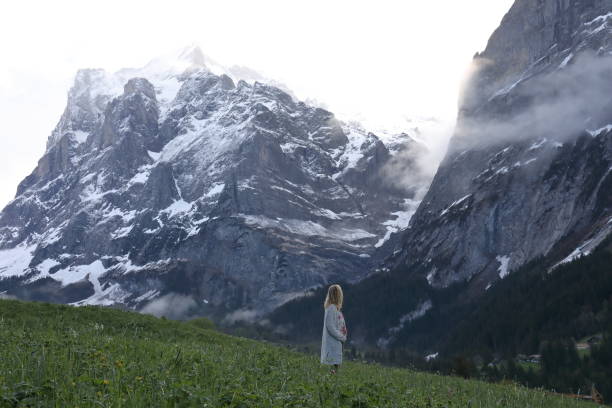 istock Woman walks into meadow, below towering mountains 1018439274