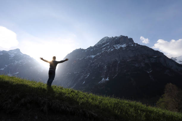istock Man walks into meadow, below towering mountains 1018439730