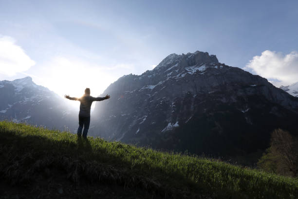 istock Man walks into meadow, below towering mountains 1018441948