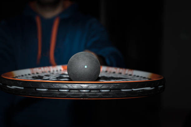 Single dot squash ball on the strings of a racquet