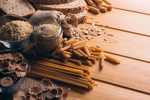 Mesa de madera llena de alimentos con cereales integrales ricos en fibra, ideales para una dieta equilibrada photo