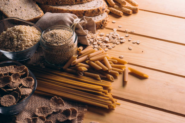 mesa de madera llena de alimentos con cereales integrales ricos en fibra, ideales para una dieta equilibrada - grano entero fotos fotografías e imágenes de stock