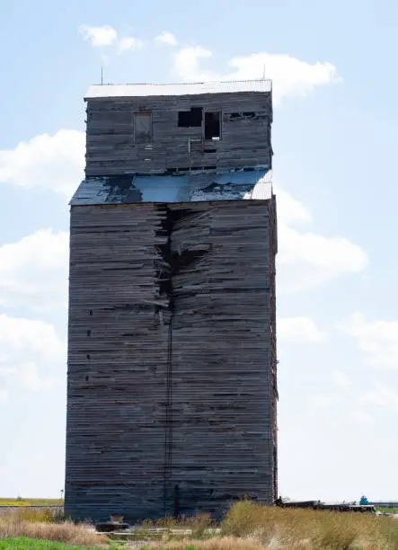 An old, rundown, damaged wooden grain elevator in rural Montana.