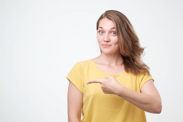 istock Young beautiful woman is pointing at the object on the left. 1018488618