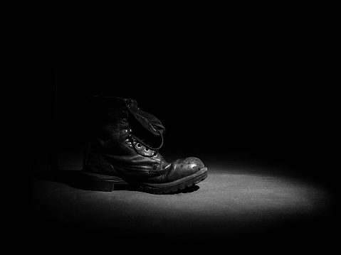 Old military shoe in a ray of light in black and white.