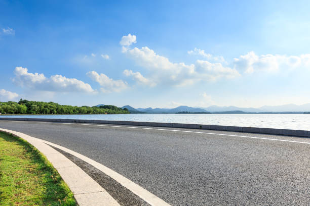 istock New asphalt road and lake with mountains on a sunny day 1018521966