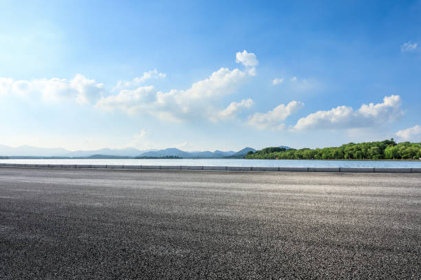 istock New asphalt road and lake with mountains on a sunny day 1018524608