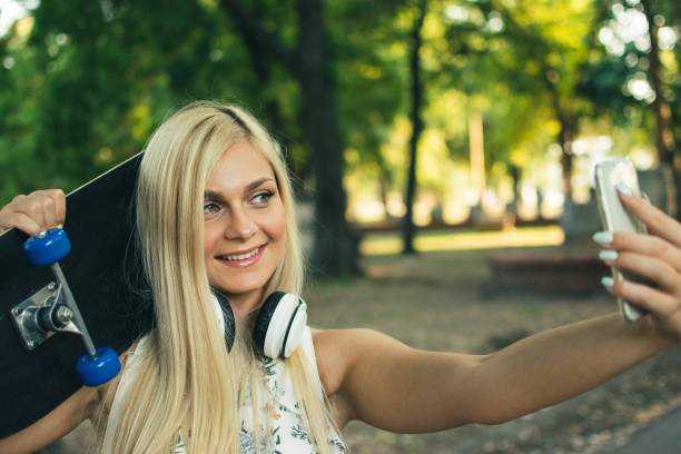 istock Smiling woman taking a selfie holding skateboard 1018524704