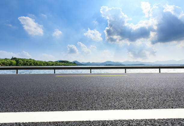 istock New asphalt road and lake with mountains on a sunny day 1018524914