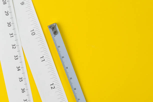 White measuring tapes with centimetre and inches on vivid yellow background with copy space, length, long or maker concept White measuring tapes with centimetre and inches on vivid yellow background with copy space, length, long or maker concept. centimetre stock pictures, royalty-free photos & images