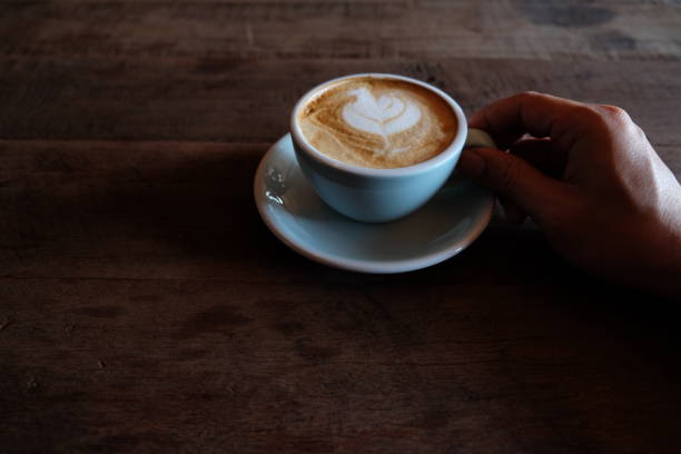 istock hands holding hot cup of coffee on rustic wooden table background 1018545878