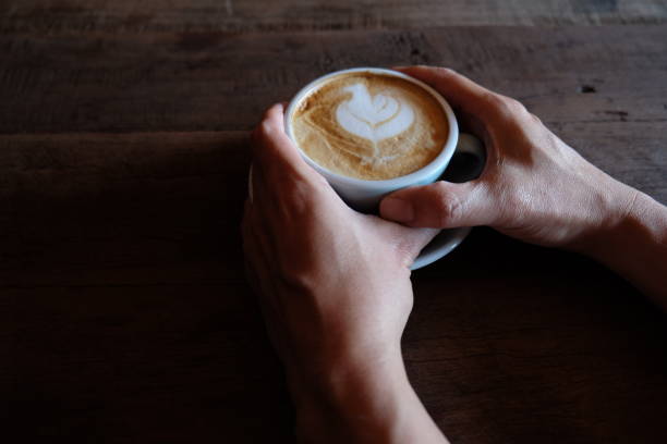 hands holding hot cup of coffee on rustic wooden table background