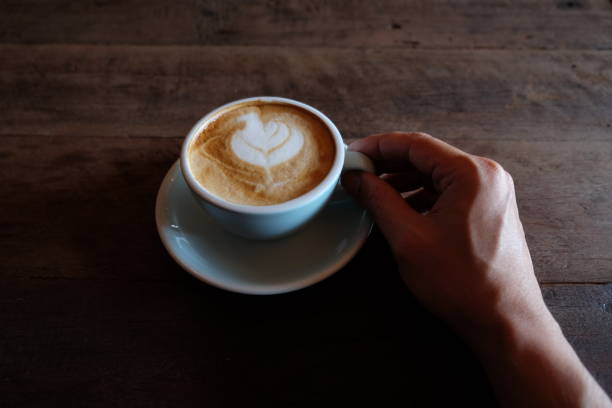 istock hands holding hot cup of coffee on rustic wooden table background 1018545908