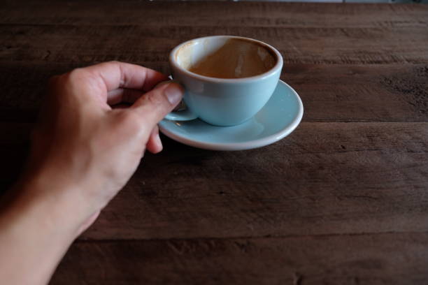 istock hands holding hot cup of coffee on rustic wooden table background 1018545960