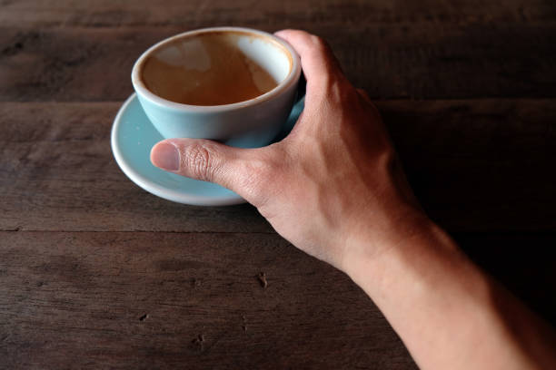 istock hands holding hot cup of coffee on rustic wooden table background 1018545980