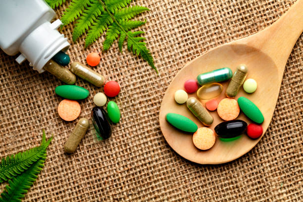 istock Close up of assorted capsules and pills into wooden spoon on a rustic background 1018548584