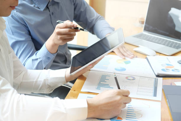 istock Attractive Asian businesspeople using tablet and laptop in modern office. 1018557878