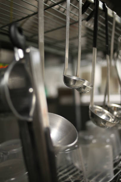 Ladles Hanging from a Stainless Steel Silver Metal Rack in an Industrial Kitchen
