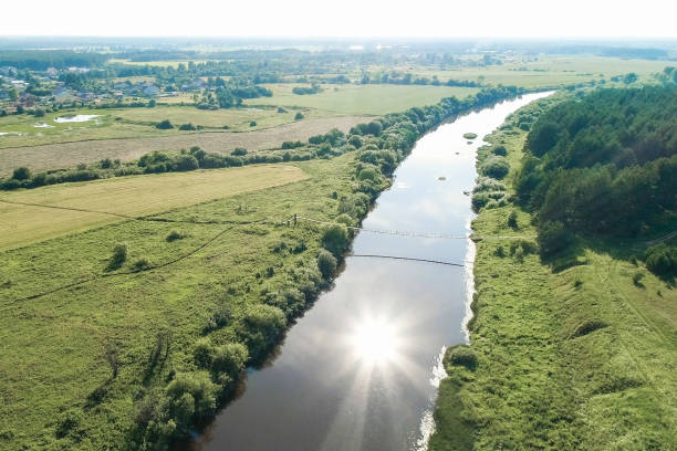 istock Flying over the village, fields, river and forests. Beautiful bird's-eye view on hanging old bridge over the river. 1018618446