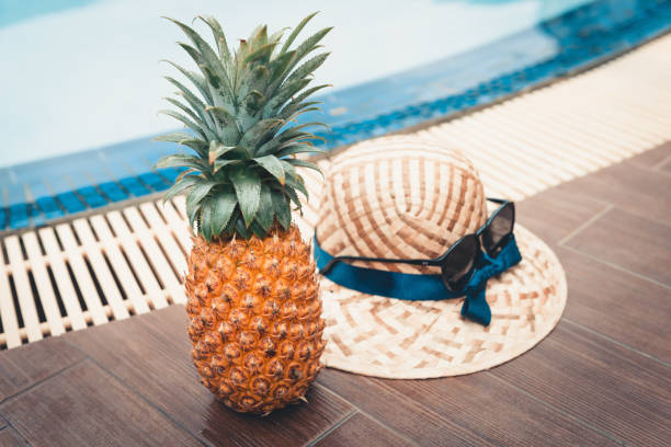 istock Summer vacation concept, Pineapple and women hat beside swimming pool 1018632036