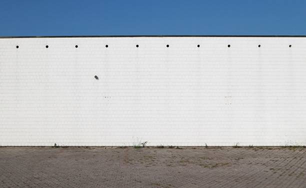 istock Urban background. Concrete road, a white wall  made of square bricks and blue sky 1018639308