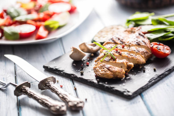 istock Grilled chicken breast on slate board herb spinach tomatoes and other vegetable. 1018652344