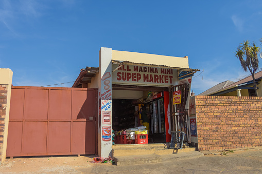 Johannesburg , Gauteng / South Africa -August 02 2018 : small Spaza African shop, showing variety of goods for sale, hot daytime, blue sky in the background, man inside the store, horizontal shot
