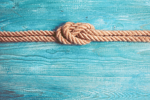 Rope, knot and wooden background