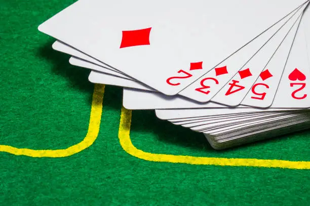 Photo of deck of playing cards on a green canvas for a poker game closeup