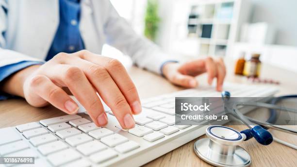 Female Doctor Typing On Computer Stock Photo - Download Image Now - Doctor, Healthcare And Medicine, Computer