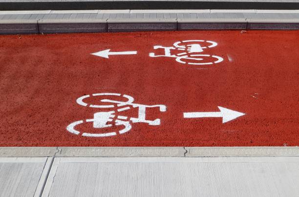 pista ciclabile a due corsie dipinta di rosso e bianco. le frecce direzionali, dopo il simbolo delle biciclette, indicano direzioni opposte - two way traffic foto e immagini stock