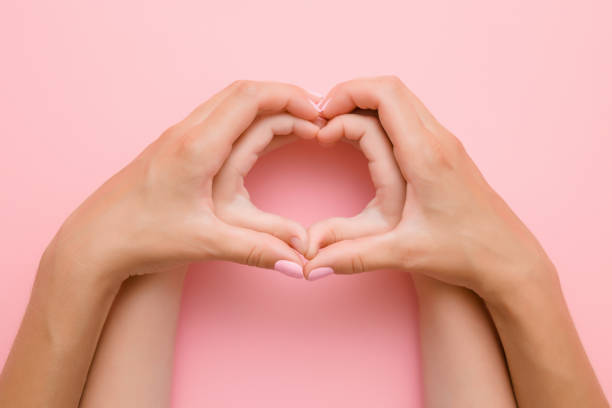 créé à partir des mains de petite fille et des mains sa mère sur le fond rose en forme de cœur. joli moment émotionnel, sentimental. concept de l’amour, de bonheur et de sécurité. - mothers day photos photos et images de collection