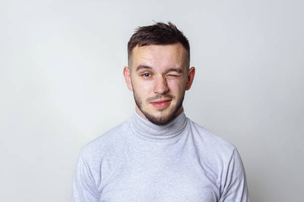 Handsome man looking at camera and winking. isolated on gray, copy space