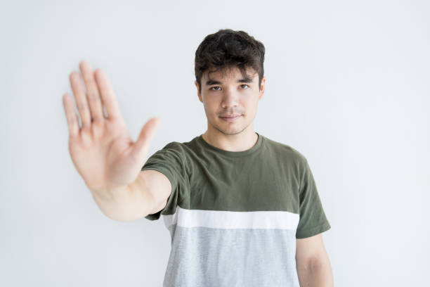 Profile of serious young Asian man showing stop gesture Profile of serious young Asian man showing stop gesture. Confident Vietnamese man standing with outstretched hand. Forbiddance concept male is standing and shows outstretched hand with open palm stock pictures, royalty-free photos & images