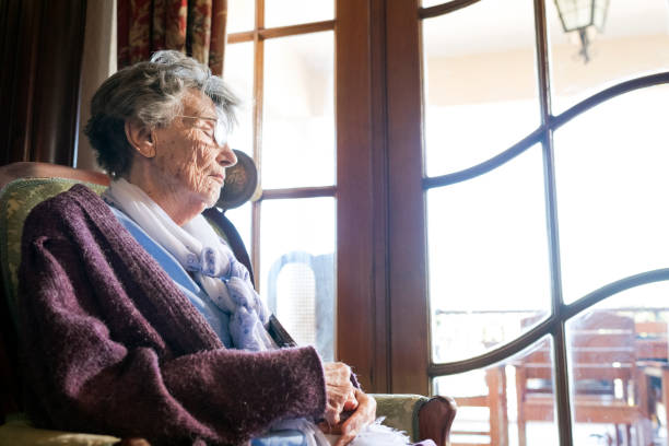 istock Senior woman sitting by a window with her eyes closed 1018719364