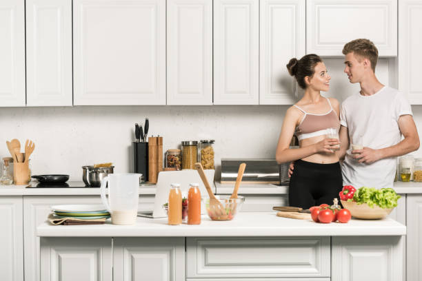istock young couple hugging and looking at each other in kitchen 1018721818