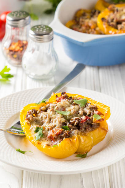 istock Stuffed yellow bell peppers, beef stew stuffing with vegetables and cheese. Light wooden background 1018735558