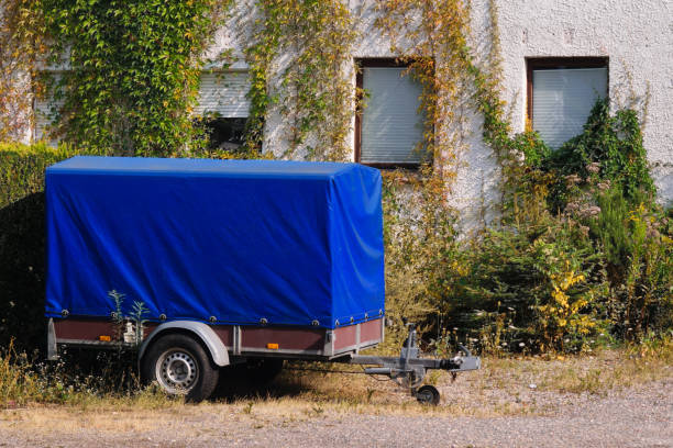 istock Old blue trailer parked next to an old house with ivy 1018735582